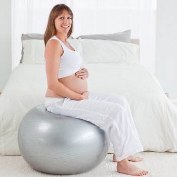una mujer joven embarazada apoyada en una pelota de fitness hace ejercicios  para fortalecer su piso pélvico y de espalda durante el embarazo Fotografía  de stock - Alamy