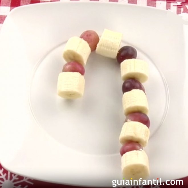 Postre de fruta navideño. Bastón de caramelo para niños