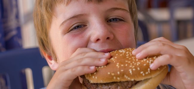 Las carnes procesadas, producen cáncer Niño come hamburguesa