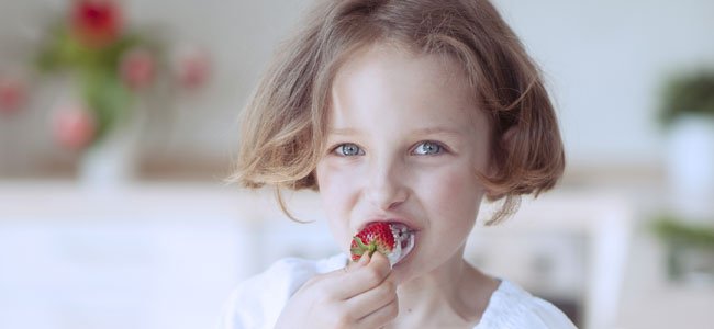 Recetas de postres con frutas Niña come fresa