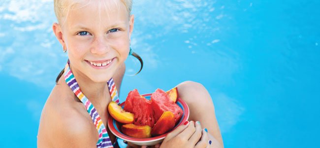 Qué a portan las frutas a los niños Niña con cuenco de fruta