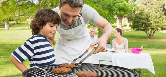 El peligro de cocinar en una barbacoa Niño y padre con barbacoa