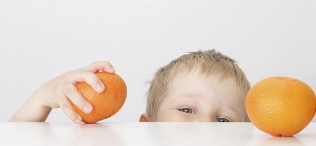 7 alimentos que cuidan el corazón de los niños Niño agarra naranja