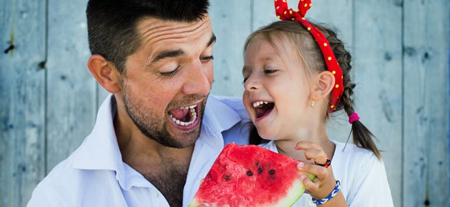 Padre con niña come sandía