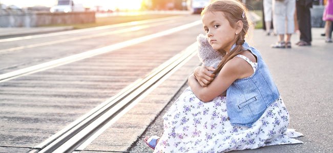 Guía rápida para actuar en caso de desaparición de un menor Niña sentada en andén