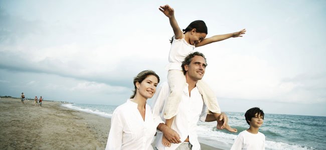 La felicidad de los padres y sus hijos Padres con hijos pasean por playa