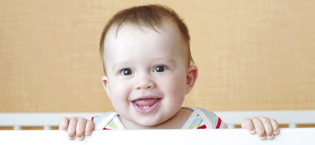 Bebé de pie en la cuna