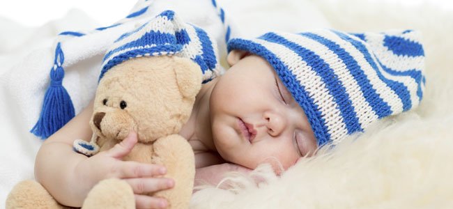 Bebé duerme abrazado a un osito de peluche