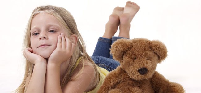 Niños que se aburren con demasiados juguetes Niña aburrida con osito