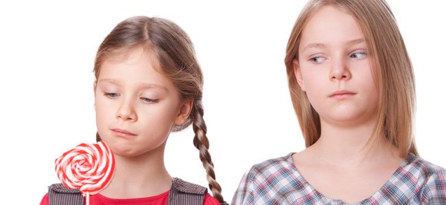 Niña mira la piruleta de otra