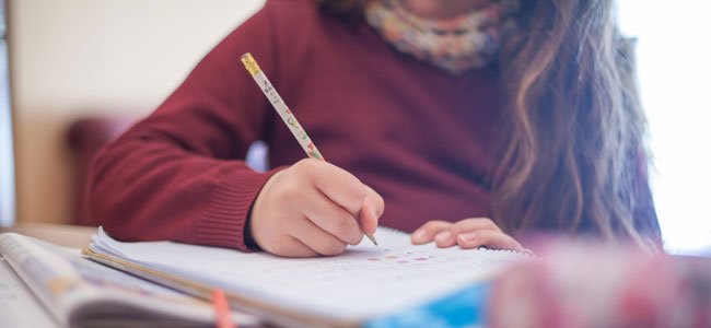 ¿Cuánto tiempo al día deben dedicar los niños a los deberes? Niña hace deberes