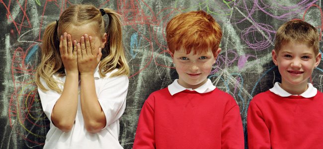 Cómo tratar los problemas de habilidades sociales en los niños Niña tímida se tapa cara