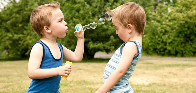 Niño echa pompas de jabón a otro