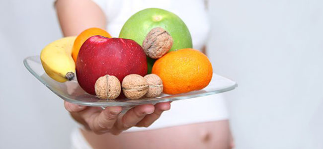 Embarazada con plato de fruta y nueces