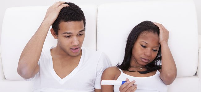 Hombre y mujer en la cama con prueba embarazo