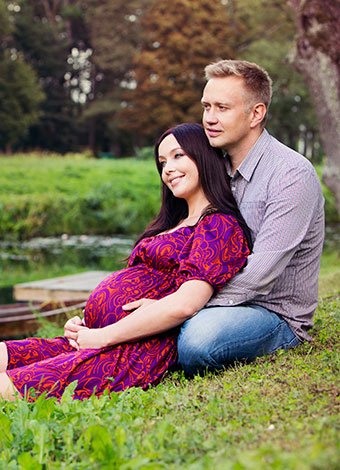 Pareja embarazada descansando junto a un rio