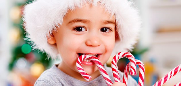 Cómo afectan los dulces a los dientes de los niños Niño come dulce navideño