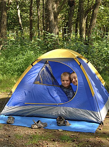 Dormir en casa de amigos o en un campamento Niños dentro de una tienda de campana