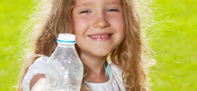 Niña sosteniendo botellas de agua de plástico para su reciclaje
