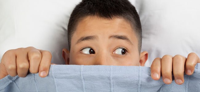 Niño asustado en cama por enuresis