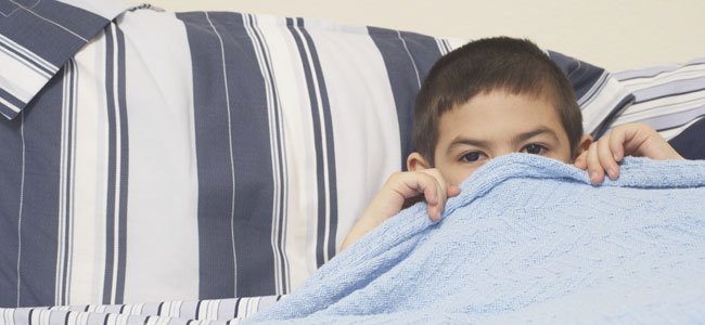 Niño se tapa en la cama con sábana