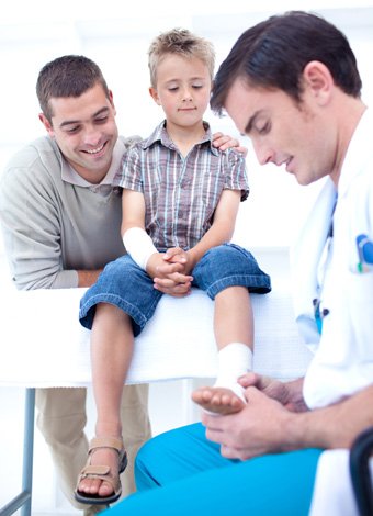 Médico vendando tobillo de niño