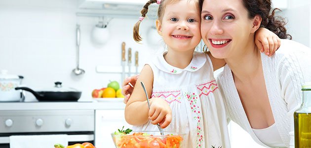 Contra la obesidad infantil, las recetas de mamá Niña con madre en la cocina