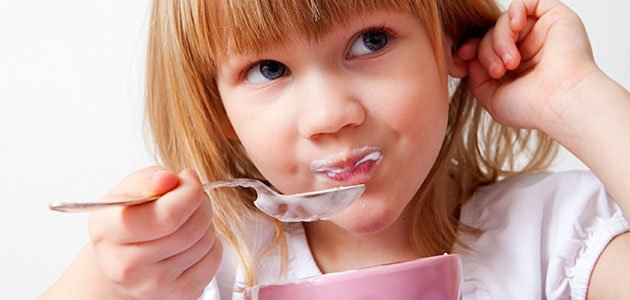 Soja para alimentar a los niños niña come yogur