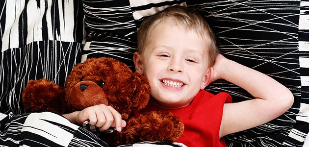 Causas del bruxismo infantil NIño en la cama con osito