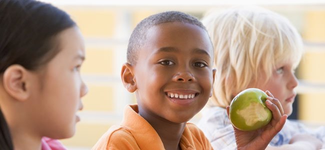 La dieta de los niños celiacos Niño negro come manzana