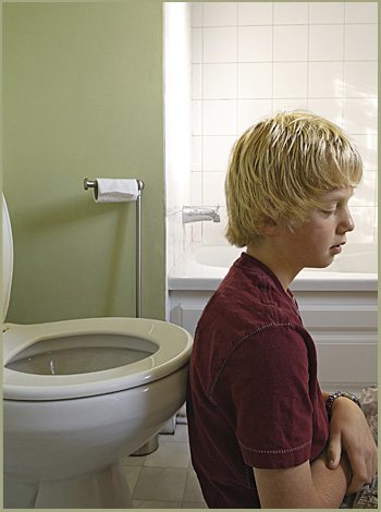 Niño con enuresis frente al retrete Niño con enuresis frente al retrete